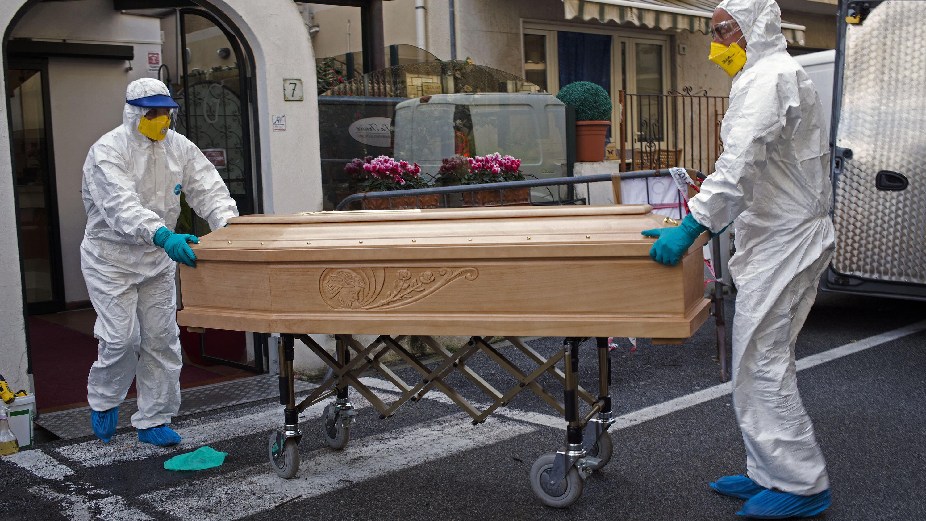 01.03.2020, Italien, Laigueglia: Medizinisches Personal in Schutzanzügen trägt einen Sarg mit dem Leichnam einer 87-jährigen Frau aus einem Hotel, nachdem sie in ihrem Zimmer verstorben ist. Die Frau, die zu einer Gruppe älterer Touristen aus der Reg