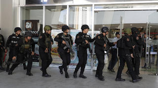 Police enter a mall in Manila, Philippines Monday, March 2, 2020. Philippine police on Monday surrounded the shopping mall in an upscale section of Manila after a recently dismissed security guard opened fire and took dozens of people hostage, an official said. (AP Photo/Aaron Favila)