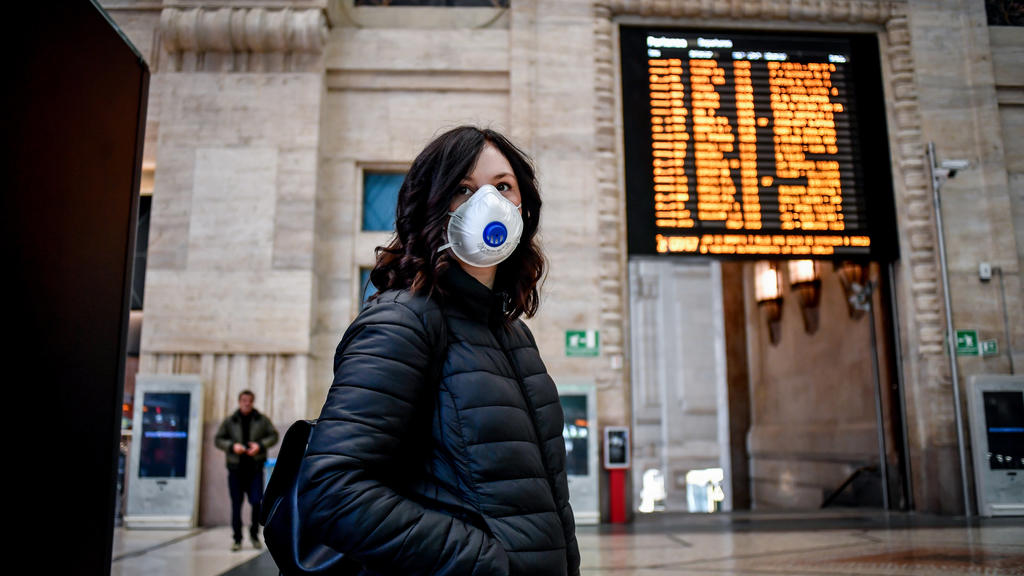 08.03.2020, Italien, Mailand: Eine Passantin mit Atemschutz steht im Hauptbahnhof. Im Kampf gegen das neue Coronavirus schränkt Italien die Bewegungsfreiheit von Bürgern im Norden drastisch ein. Die Menschen in der wirtschaftsstarken Lombardei und 14