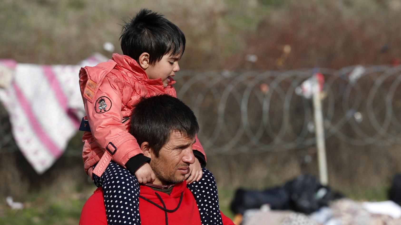 Ein Mann trägt seinen Sohn auf einem Feld nahe der türkisch-griechischen Grenze auf der Schulter.