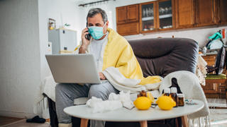 Mann mit einer Virus-Infektion sitzt zu Hause unter Quarantäne