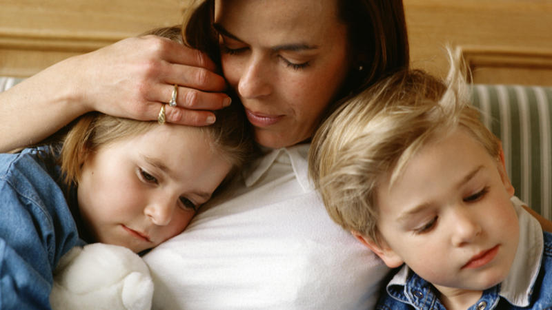 Eine Mutter hält ihre zwei Kinder im Arm.