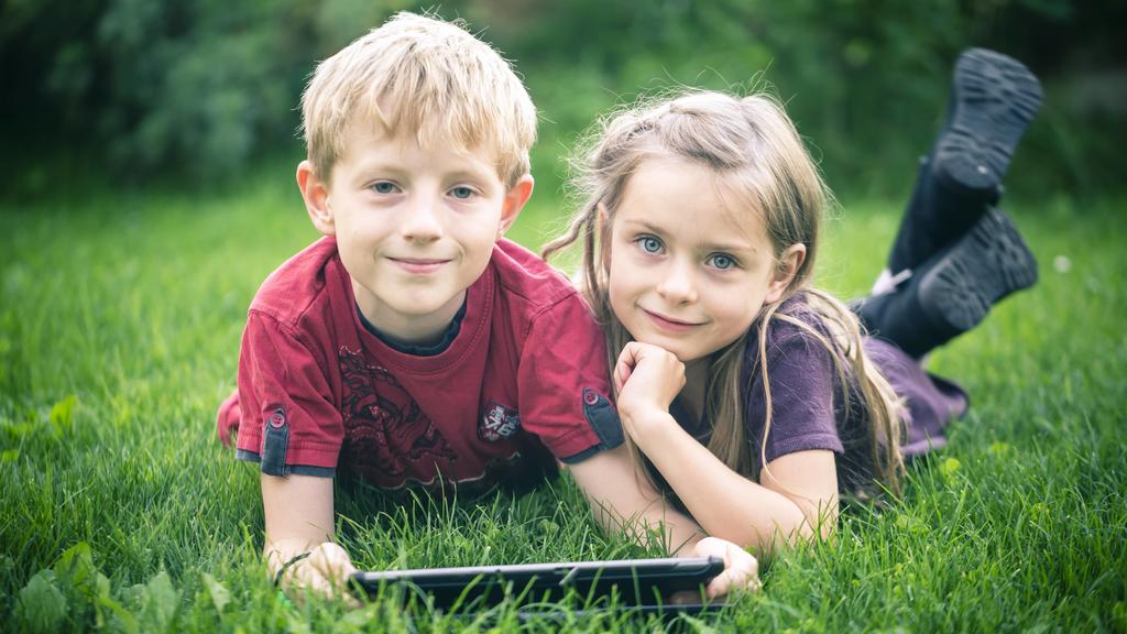 Portrait of brother and sister lying on a meadow with digital tablet model released Symbolfoto PUBLICATIONxINxGERxSUIxAUTxHUNxONLY SARF000868
