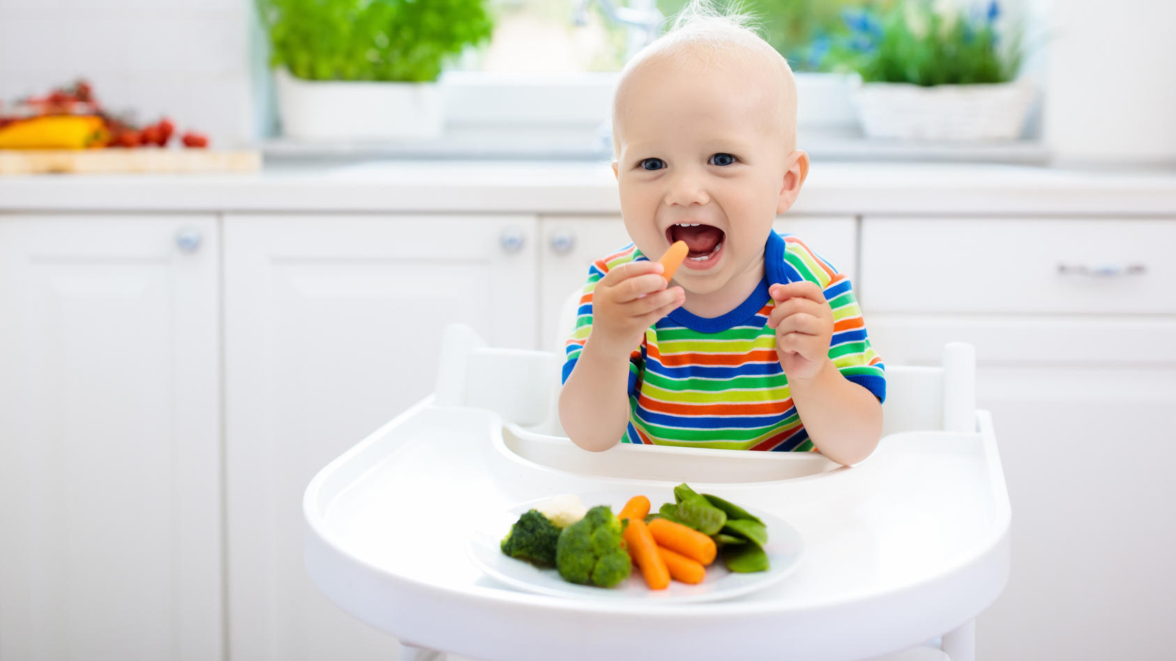 Fröhliches Baby isst Gemüse