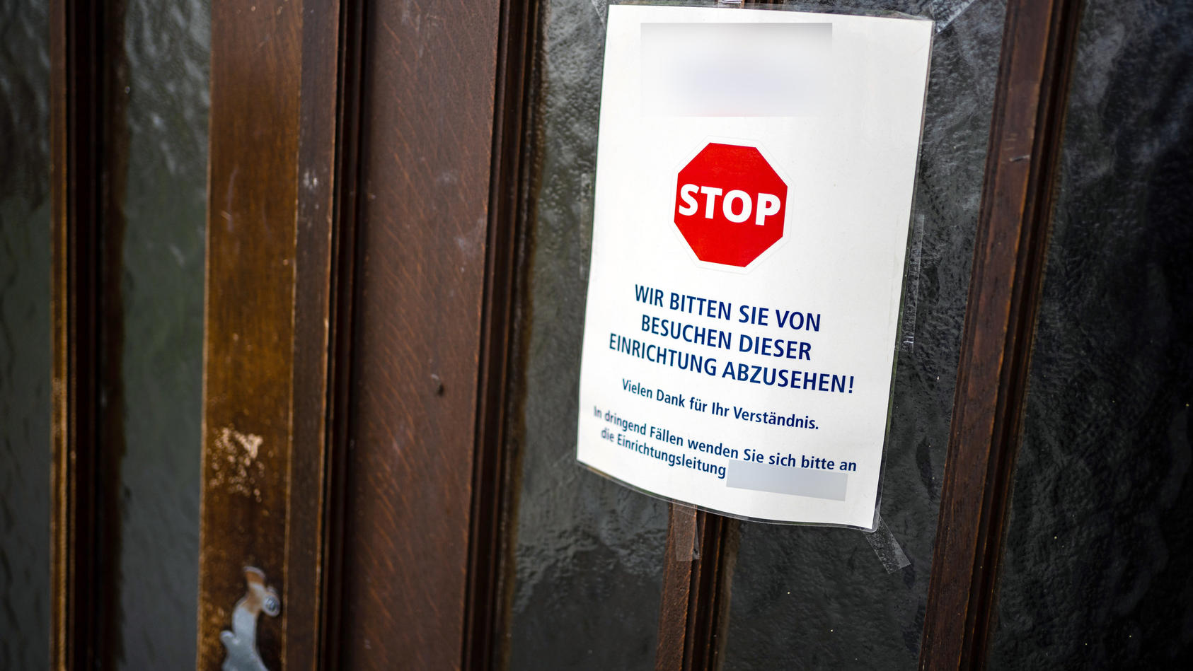 An einer Zugangstür zu einem Seniorenheim ist ein Schild angebracht, das von Besuchen dieser Einrichtung abrät. In dem Würzburger Seniorenheim gab es bisher drei Todesfälle.