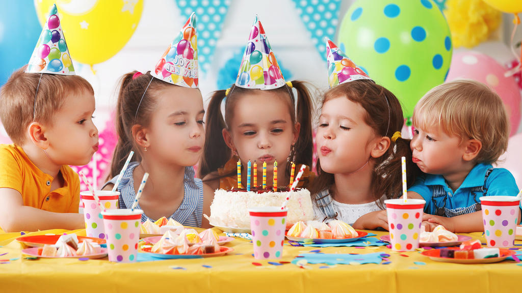 Kinder stecken die Köpfe zusammen auf Kindergeburtstag - keine gute Idee in Corona-Zeiten