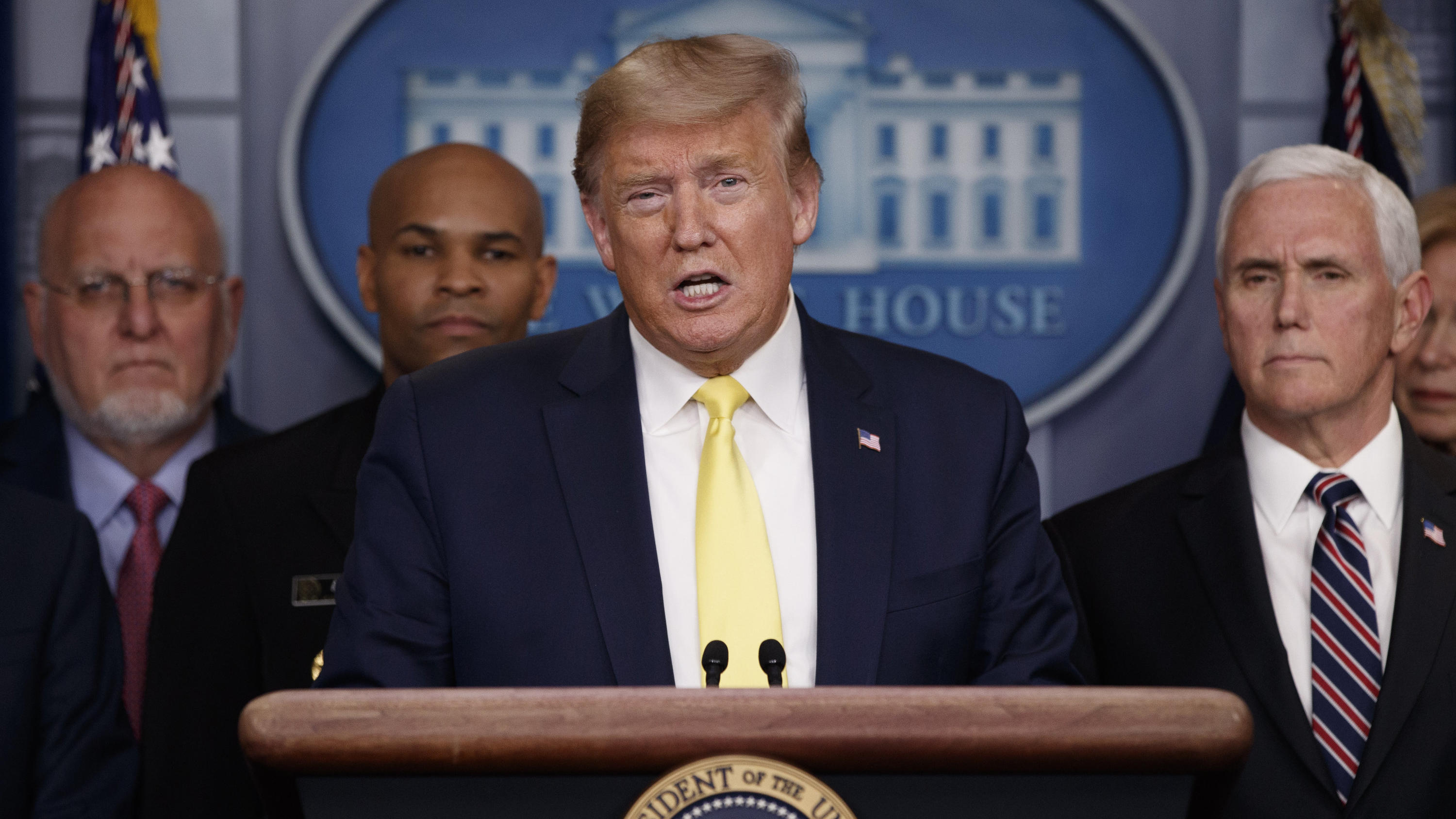 In this March 9, 2020, photo, President Donald Trump speaks in the briefing room of the White House in Washington about the coronavirus outbreak as Dr. Robert Redfield, director of the Centers for Disease Control and Prevention, Surgeon General Jerom