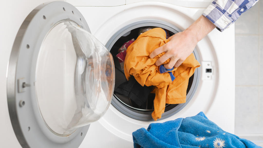 Frau legt dreckige Wäsche in die Waschmaschine.
