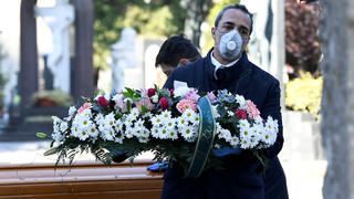 FILE PHOTO: Cemetery workers and funeral agency workers in protective masks transport a coffin of a person who died from coronavirus disease (COVID-19), into a cemetery in Bergamo, Italy March 16, 2020. REUTERS/Flavio Lo Scalzo/File Photo