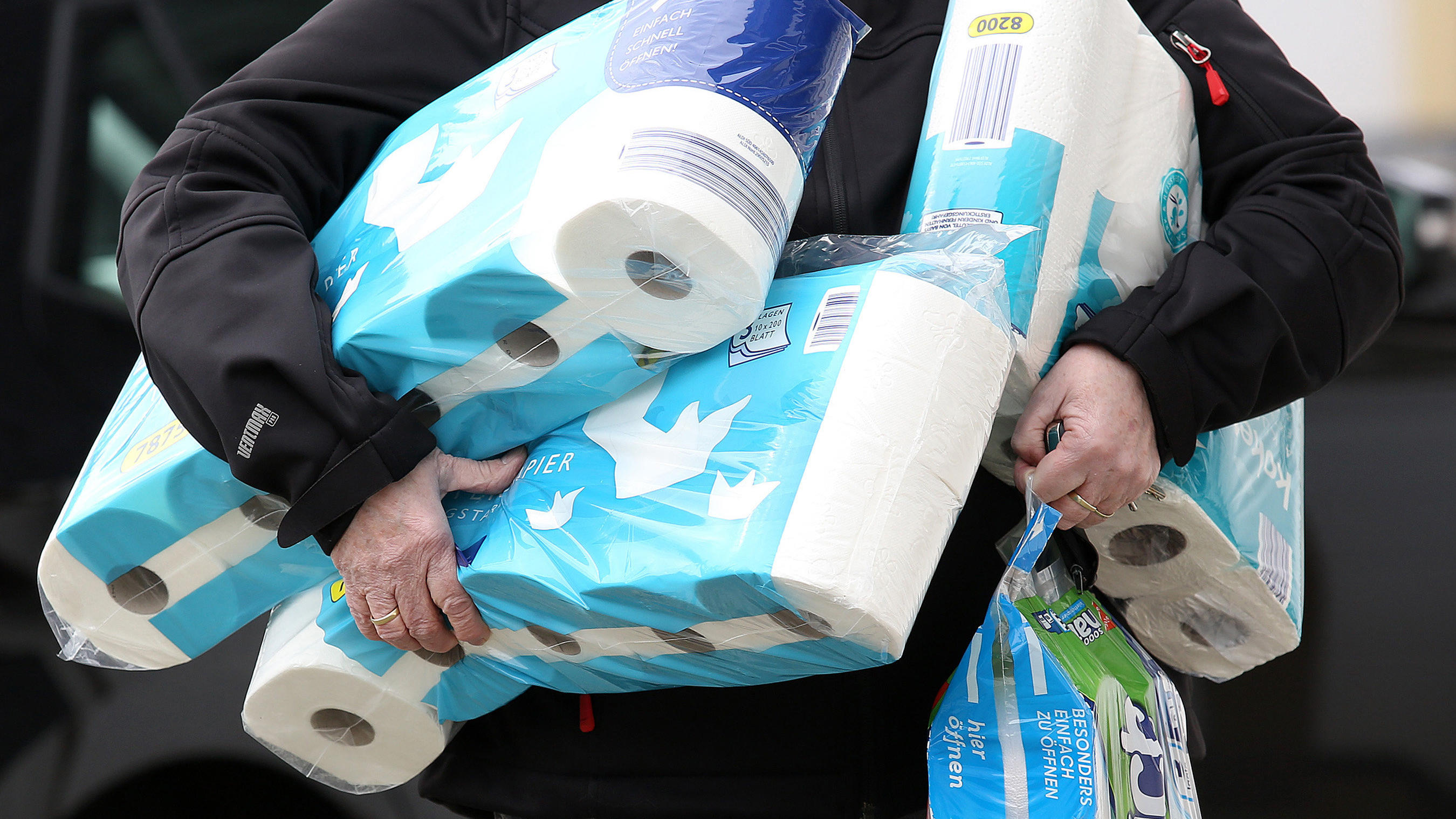 ARCHIV - 18.03.2020, Nordrhein-Westfalen, Siegen: Ein Mann trägt eingekauftes Toilettenpapier und Küchenrollen aus einem Supermarkt. Auch wenn das neuartige Coronavirus beängstigend ist, haben viele Menschen ihren Humor noch nicht verloren. So leer, 