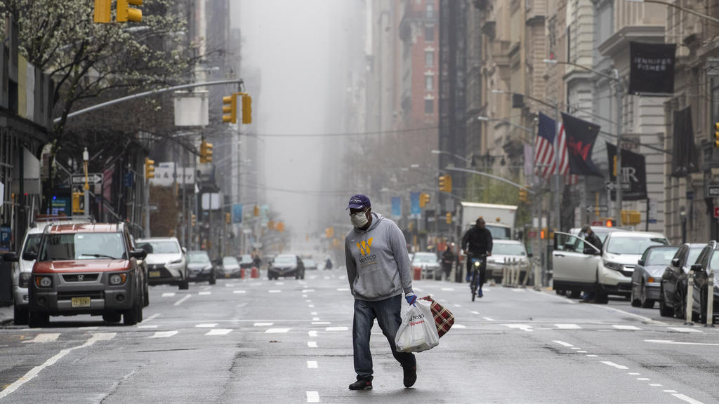 29.03.2020, USA, New York: Ein Mann trägt eine Maske und geht über die 5th Avenue. Foto: Mary Altaffer/AP/dpa +++ dpa-Bildfunk +++