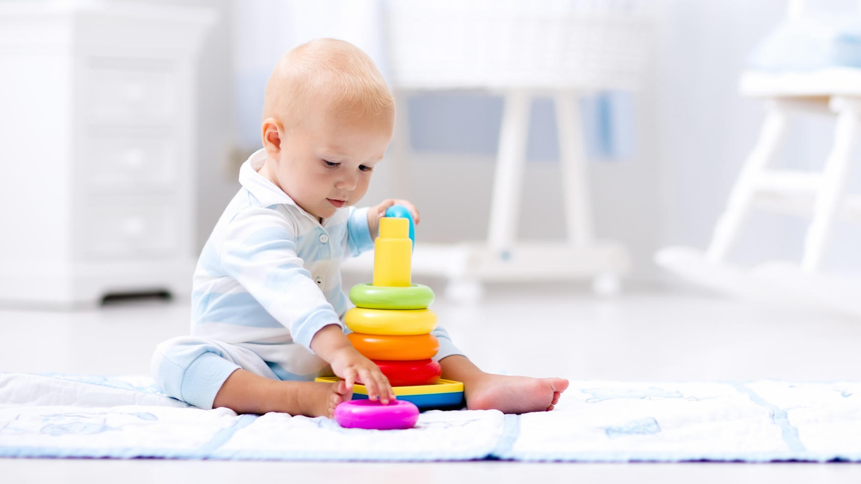 Babyentwicklung: Baby spielt mit bunten Ringen