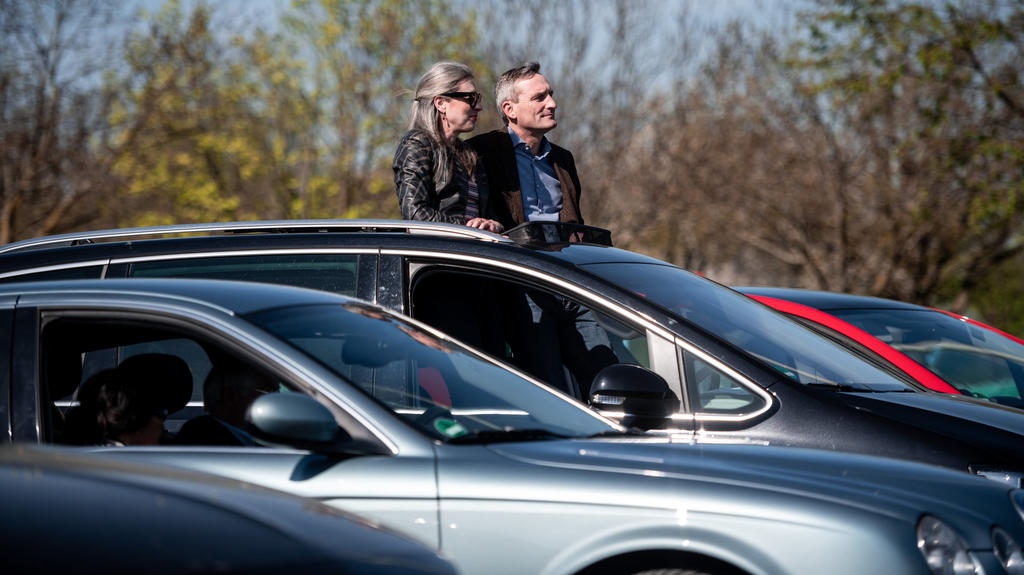 10.04.2020, Nordrhein-Westfalen, Düsseldorf: Oberbürgermeister Thomas Geisel sitzt mit seiner Frau Vera in seinem Auto und guckt aus dem Dachfenster Richtung Bühne. Trotz der Corona-Krise sollen Gläubige in einem Düsseldorfer Autokino Ostergottesdien