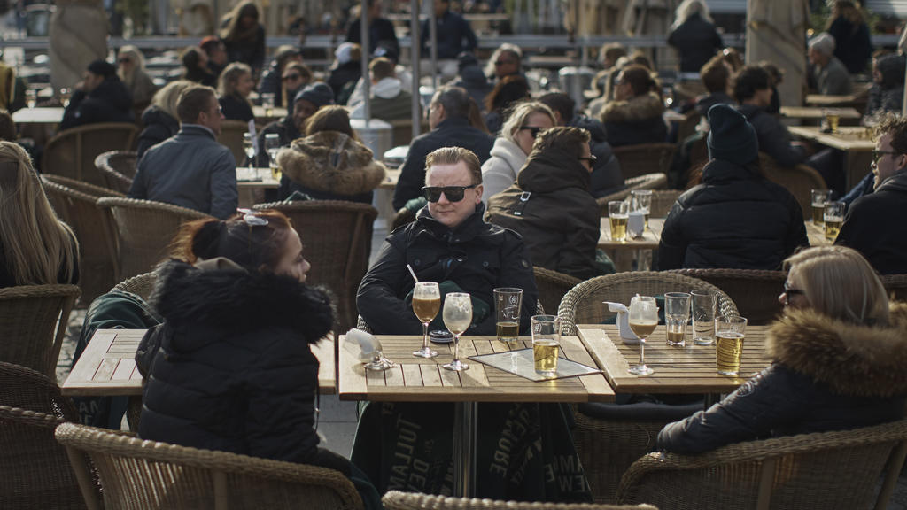 04.04.2020, Schweden, Stockholm: Menschen sitzen vor einem Restaurant am Bürgerplatz. Die Schweden gehen bisher mit freizügigeren Maßnahmen als andere europäische Länder gegen die Corona-Pandemie vor, verfolgen aber ebenso das Ziel, die Ausbreitung d