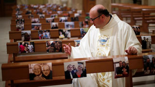 Priest Don Giancarlo Ruggieri gestures amid benches with pictures of members of the congregation, after livestreaming an Easter Sunday Mass, as Italy celebrates Easter under lockdown, due to the outbreak of the coronavirus disease (COVID-19), in the small southern town of San Giorgio Ionico, Itay April 12, 2020. REUTERS/Alessandro Garofalo