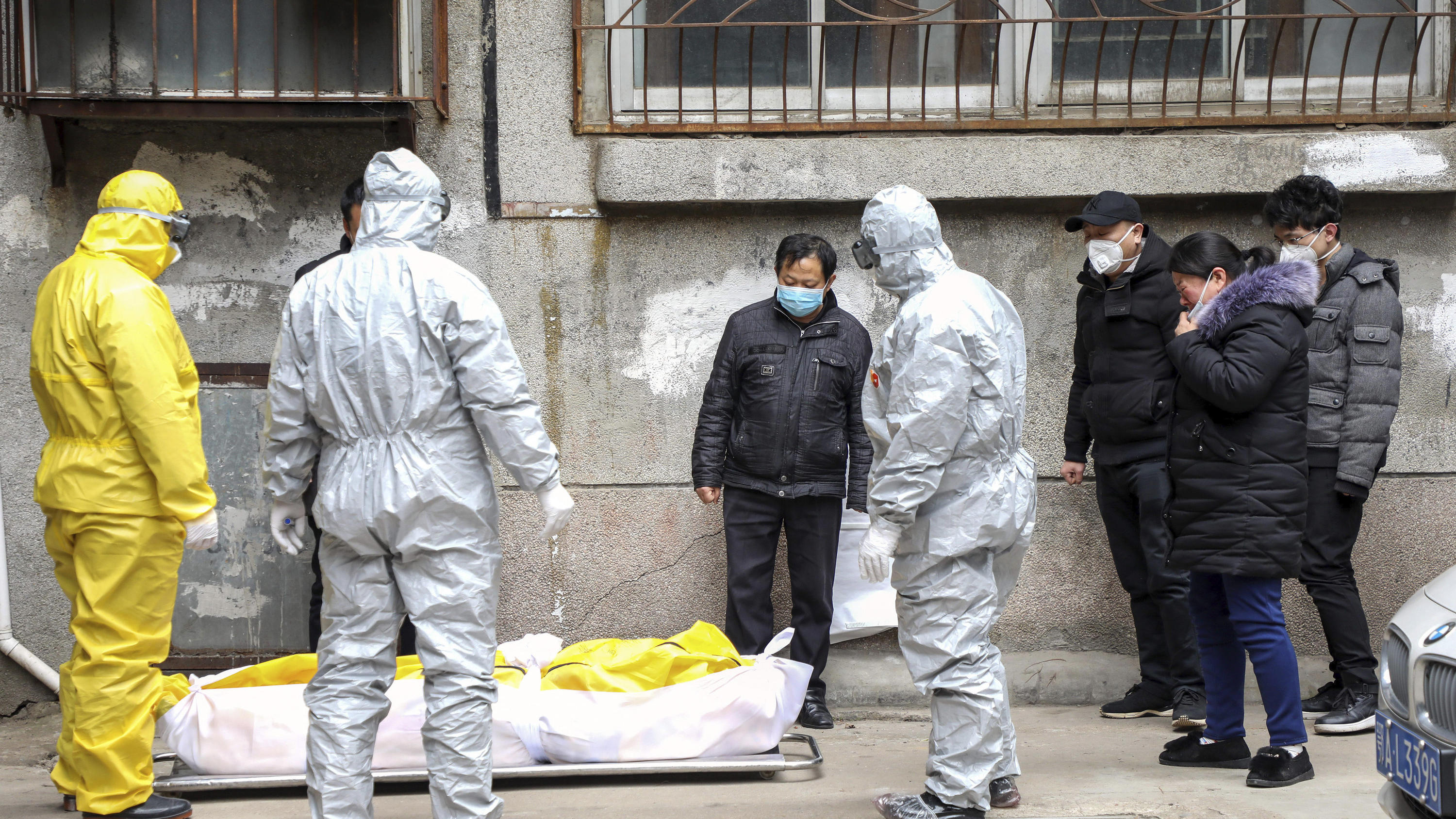 FILE - In this Feb. 1, 2020, file photo, funeral home workers remove the body of a person suspected to have died from the coronavirus outbreak from a residential building in Wuhan in central China's Hubei Province. The central Chinese city of Wuhan h