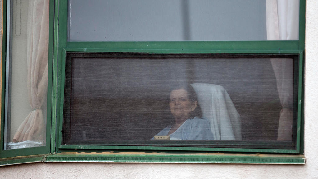 A resident looks out her window at Residence Herron, a senior's long-term care facility, following a number of deaths since the coronavirus disease (COVID-19) outbreak, in the suburb of Dorval in Montreal Quebec, Canada April 13, 2020.  REUTERS/Chris
