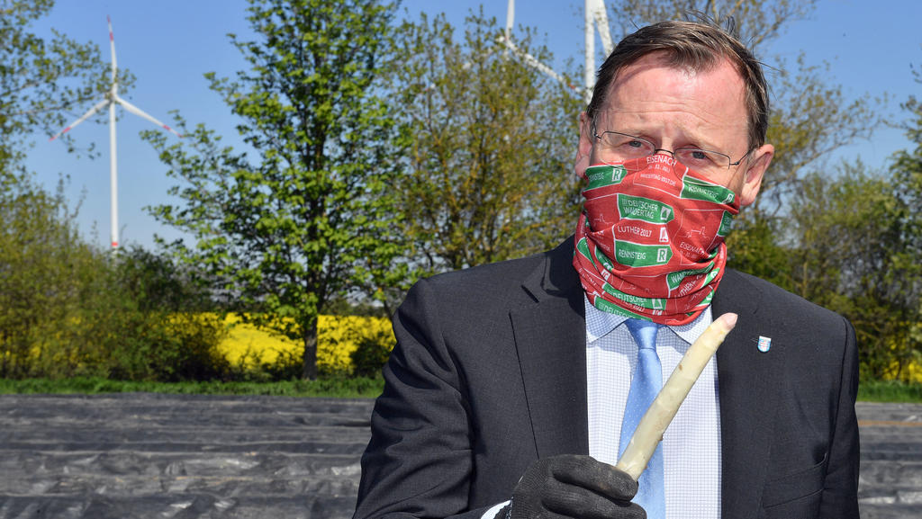 22.04.2020, Thüringen, Kutzleben: Bodo Ramelow (Die Linke), Ministerpräsident von Thüringen, präsentiert eine Spargelstange auf einem Feld des Spargelhofs Kutzleben. Der Betrieb im Unstrut-Hainich-Kreis ist einer der größten Spargelanbauer in Thüring