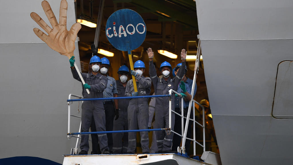 dpatopbilder - 23.04.2020, Australien, Wollongong: Besatzungsmitglieder der «Ruby Princess» winken mit Pappschildern in Form einer Hand und der Aufschrift «Ciaoo», als das Schiff den Hafen des Küstenvororts Port Kembla verlässt. Das Kreuzfahrtschiff,