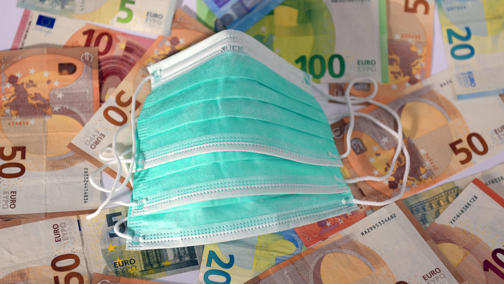 30.03.2020, Symbolbild, Corona-Krise und die Finanziellen Auswirkungen. Mundschutz liegt auf Euro-Banknoten. 30.03.2020, Kosten für Corona-Krise 30.03.2020, Kosten für Corona-Krise *** 30 03 2020, symbolic image, corona crisis and the financial impac