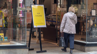 27.04.2020, Bayern, München: Eine Frau betritt ein Geschäft durch eine Tür, neben dem ein Schild mit der Aufschrift «Nur Eingang» steht. Von dieser Woche an dürfen in Bayern unter anderem Geschäfte mit bis zu 800 Quadratmetern Verkaufsfläche unter Auflagen wieder öffnen. Allerdings gilt eine strenge Mund-Nasen-Schutz-Pflicht in Läden und im öffentlichen Nahverkehr. Foto: Peter Kneffel/dpa +++ dpa-Bildfunk +++
