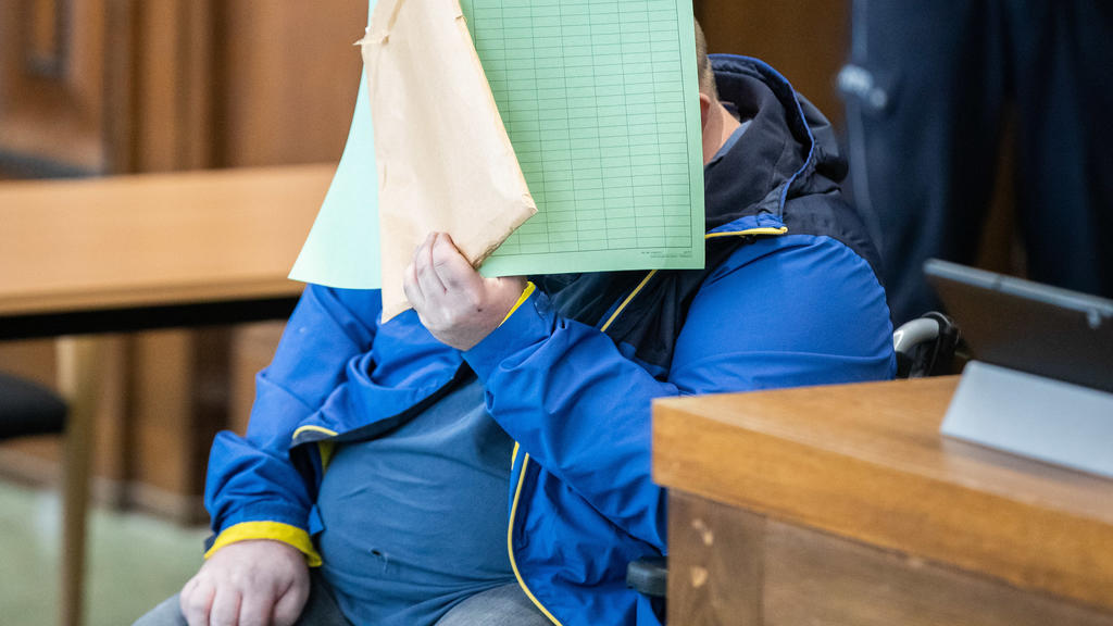 29.04.2020, Nordrhein-Westfalen, Mönchengladbach: Einer der beiden Angeklagten sitzt in einem Rollstuhl mit einer Mappe vor dem Gesicht vor Beginn der Verhandlung im Missbrauchskomplex Bergisch-Gladbach im Gerichtssaal des Landgerichts. Den 39 Jahre