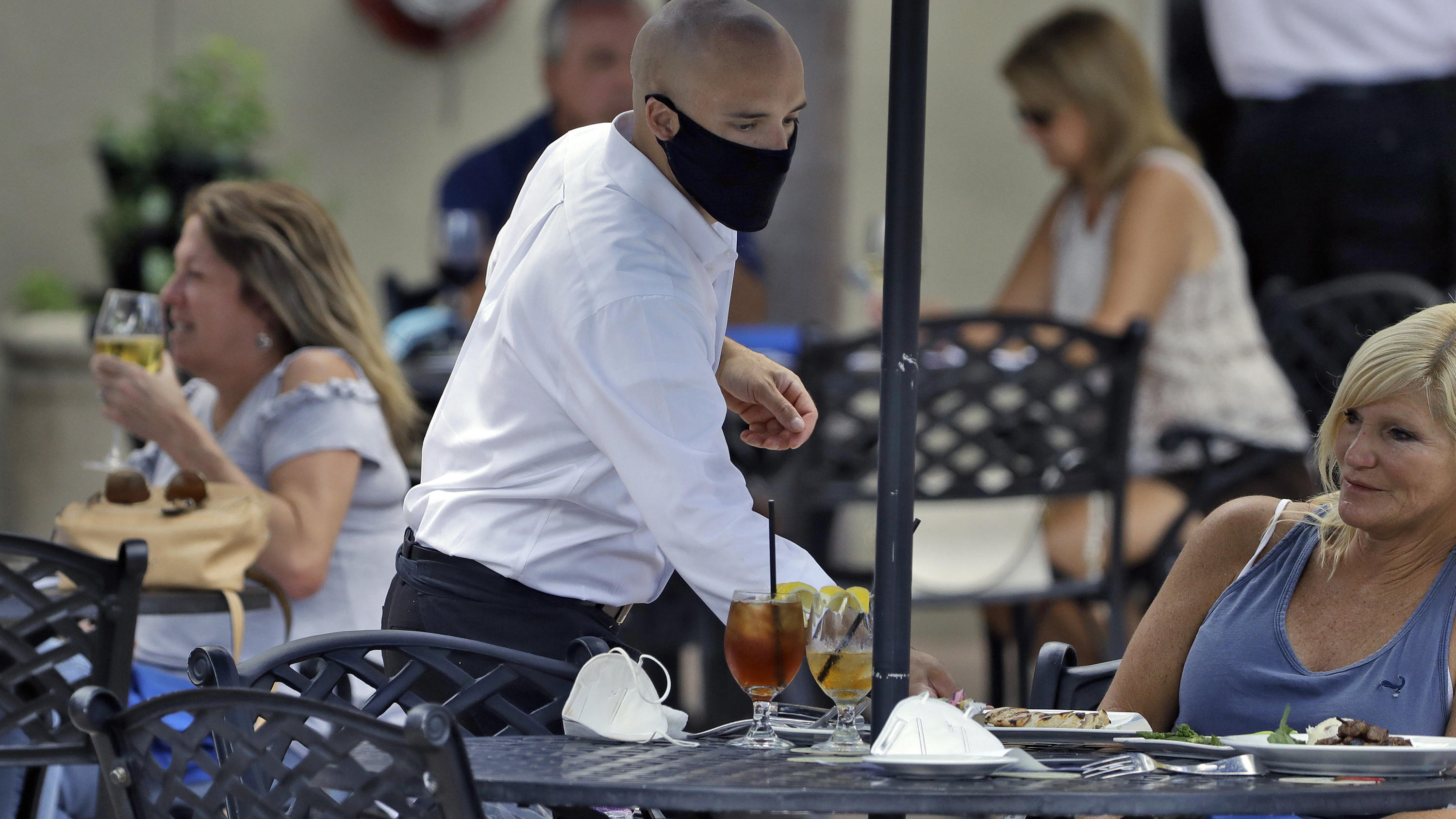 A foodserver at the Parkshore Grill restaurant wears a protective face mask as he waits on customers Monday, May 4, 2020, in St. Petersburg, Fla. Several restaurants are reopening with a 25apacity as part of Florida Gov. Ron DeSantis' plan to stop th