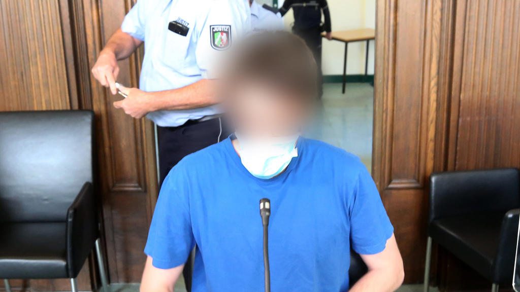 12.05.2020, Nordrhein-Westfalen, Moers: Der Angeklagte (vorne) wartet unter den Augen eines Justizbeamten auf den Beginn seines Prozesses. Der 26 Jahre alte Soldat soll kleine Kinder in insgesamt 33 Fällen missbraucht haben, teilweise schwer und zwei