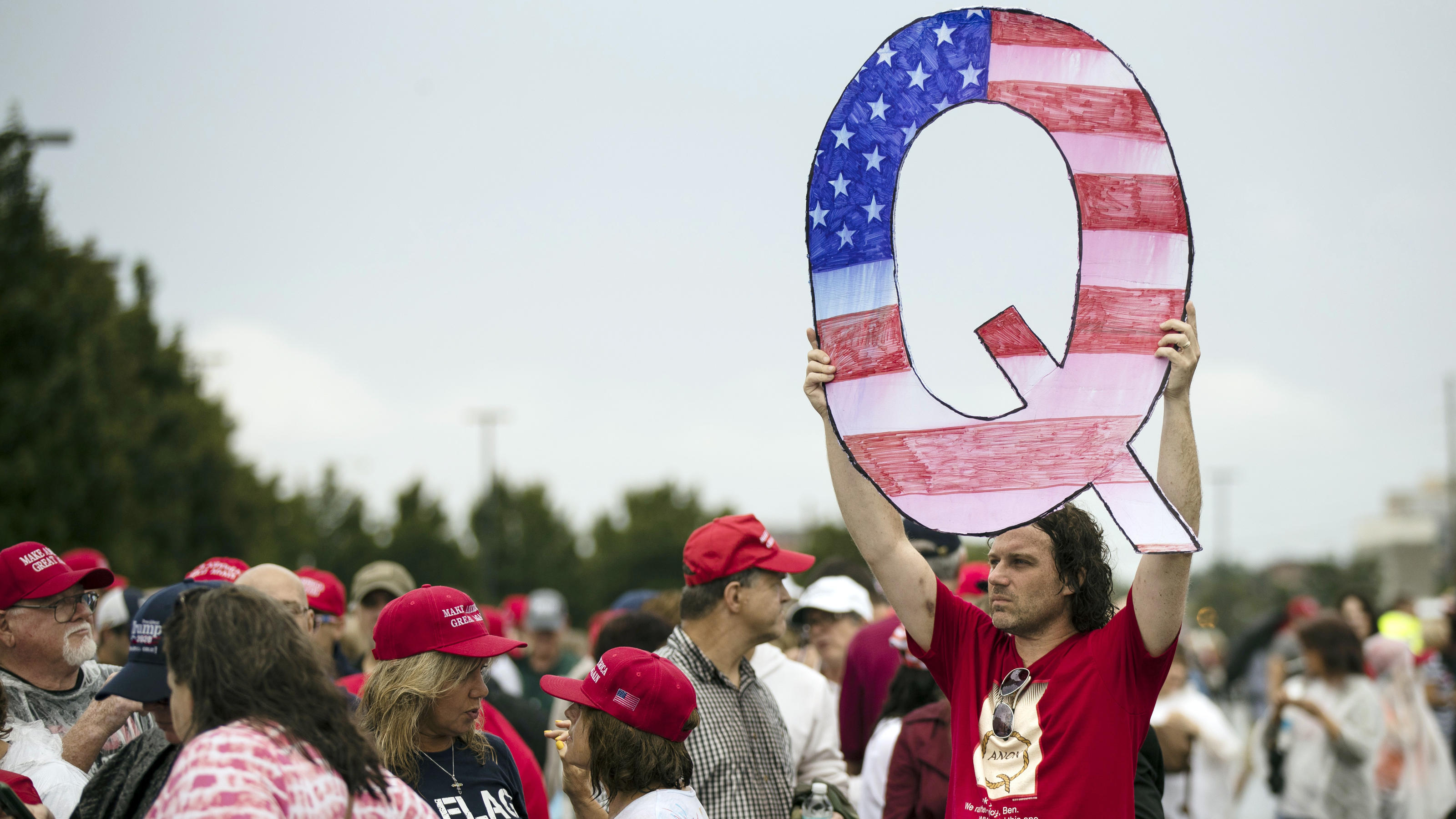 David Reinert holding a Q sign waits in line with others to enter a campaign rally with President Donald Trump and U.S. Senate candidate Rep. Lou Barletta, R-Pa., Thursday, Aug. 2, 2018, in Wilkes-Barre, Pa. (AP Photo/Matt Rourke)