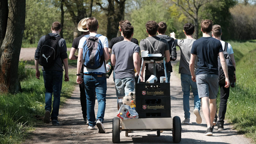 Eine Gruppe junger Männer feiert den Vatertag mit einem mit Bier gefüllten Bollerwagen.