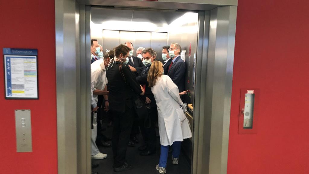 ARCHIV - 14.04.2020, Hessen, Gießen: Bei einem Besuch der Uniklinik Gießen drängen sich Bundesgesundheitsminister Jens Spahn (CDU, l), und Hessens Ministerpräsident Volker Bouffier (CDU, M) mit Begleitern in einem Fahrstuhl. Die in die Kritik geraten