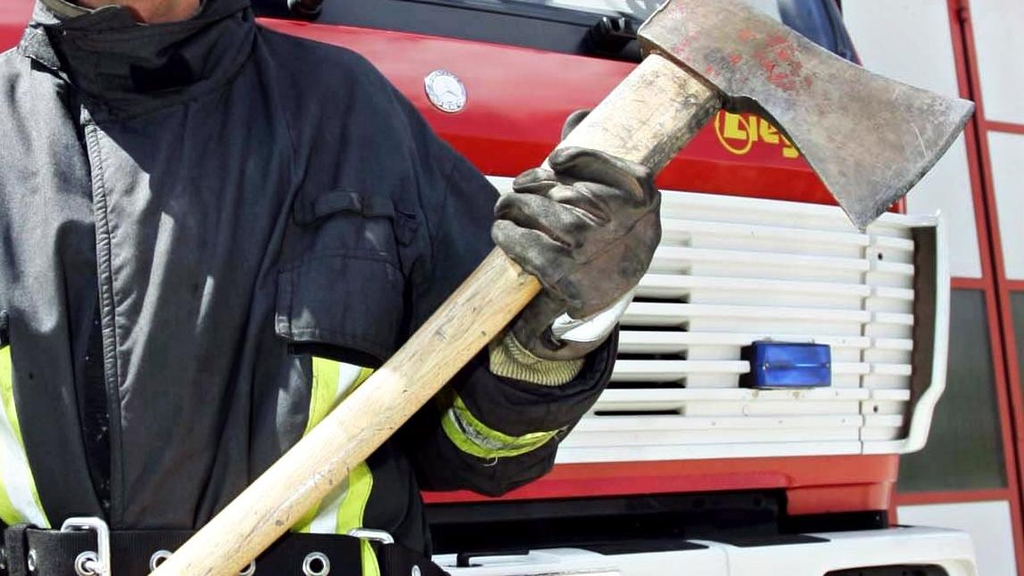 Ein junger schlanker Feuerwehrmann zwängte seinen Körper in die Einwurfklappe eines  Müllcontainers und zerstörte den Wecker mit einer Axt.