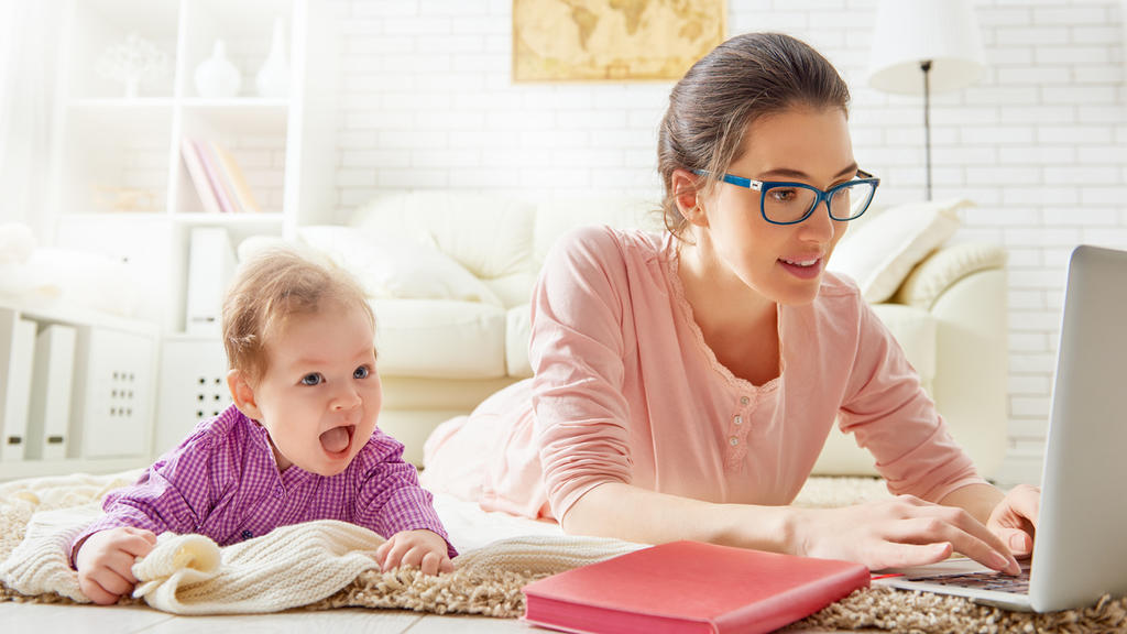 Eine Frau mit Baby arbeitet in der Elternzeit