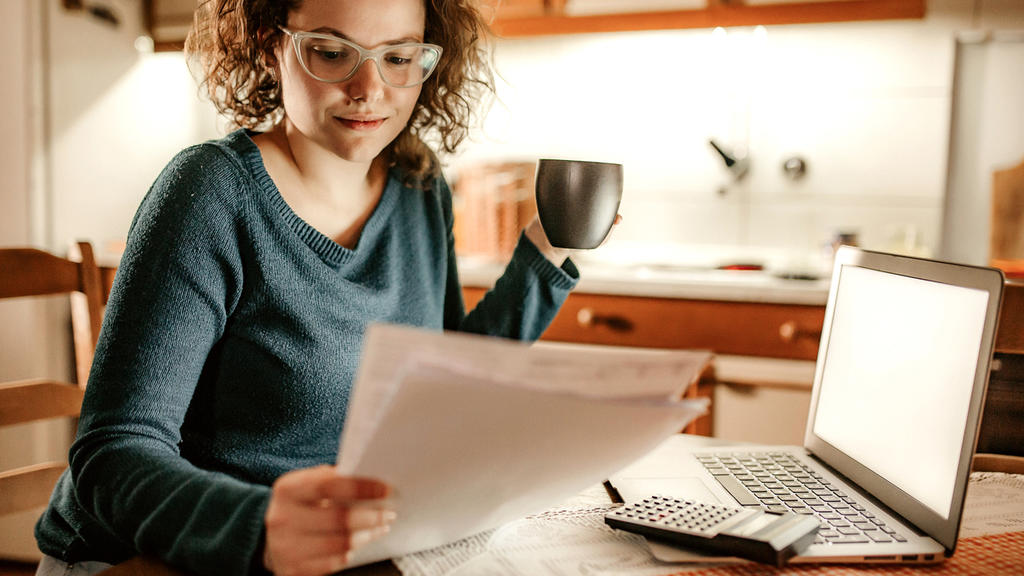 Frau rechnet ihre Finanzen durch mit einem Taschenrechner