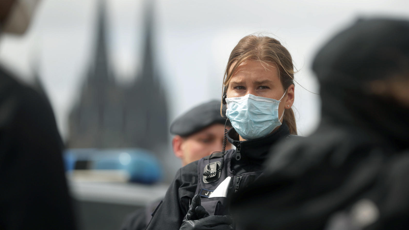 23.05.2020, Nordrhein-Westfalen, Köln: Bei einer Demonstration gegen Corona-Beschränkungen steht eine Polizistin mit medizinischem Mundschutz. Im Hintergrund der Kölner Dom. Foto: David Young/dpa +++ dpa-Bildfunk +++