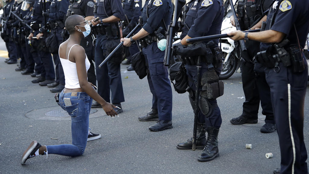 A masked protester kneels before San Jose police on Friday, May 29, 2020, in San Jose, Calif., in response to the death of George Floyd in police custody on Memorial Day in Minneapolis. (AP Photo/Ben Margot)