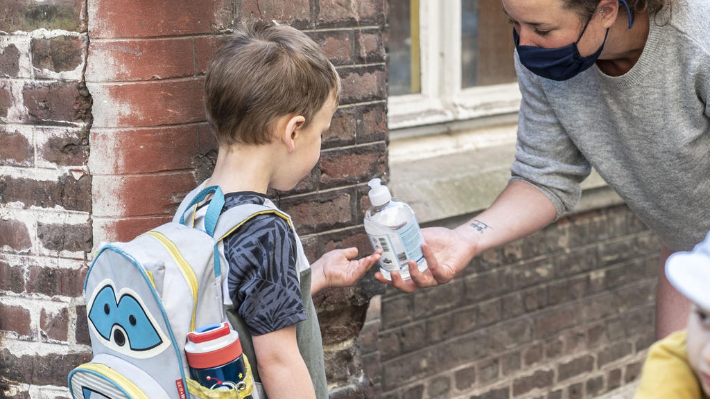 ILLUSTRATION - 02.06.2020, Belgien, Gent: Eine Lehrerin gibt einem Schüler Desinfektionsmittel am Eingang der "De Kleine Icarus"-Schule. Belgien befindet sich in der zweiten Phase der Lockerungen während der Corona-Pandemie. Im Zuge der Lockerungen g