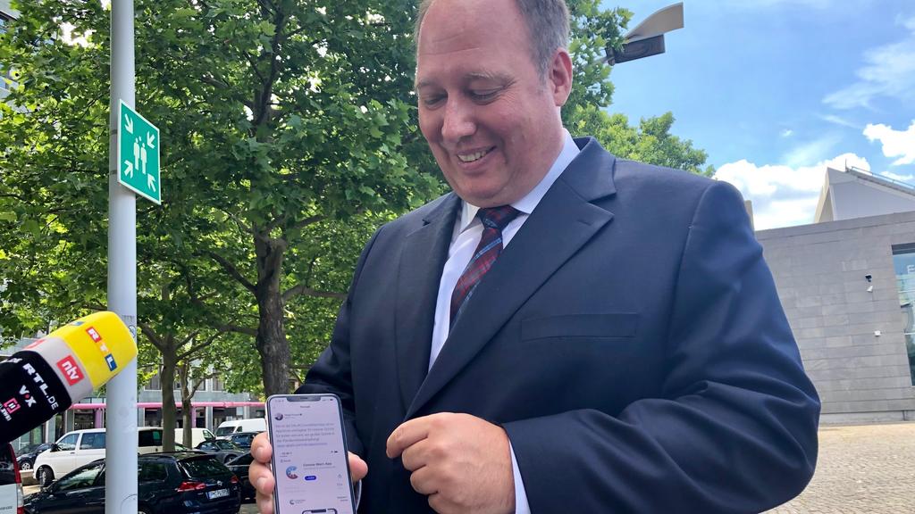 Helge Braun zeigt die Corona-Warn-App auf seinem Smartphone