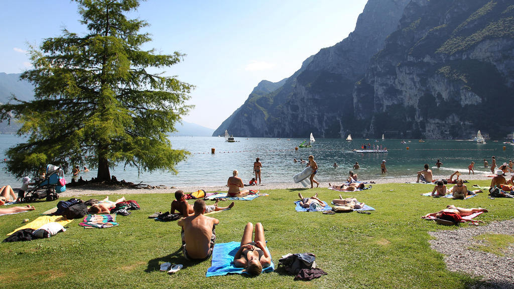 Touristen liegen am mit Gras bewachsenem Ufer des Gardasees