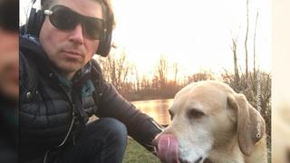Matthias Kanedlik sitzt im Gras und umarmt seinen Hund. Er macht ein Selfie.