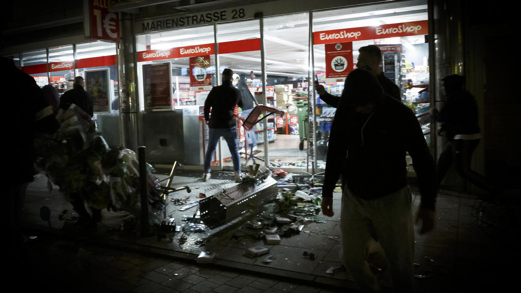 21.06.2020, Baden-Württemberg, Stuttgart: Menschen stehen vor einem geplünderten Geschäft in der Marienstraße. Bei Auseinandersetzungen mit der Polizei haben dutzende gewalttätige Kleingruppen die Innenstadt verwüstet und mehrere Beamte verletzt. Fot