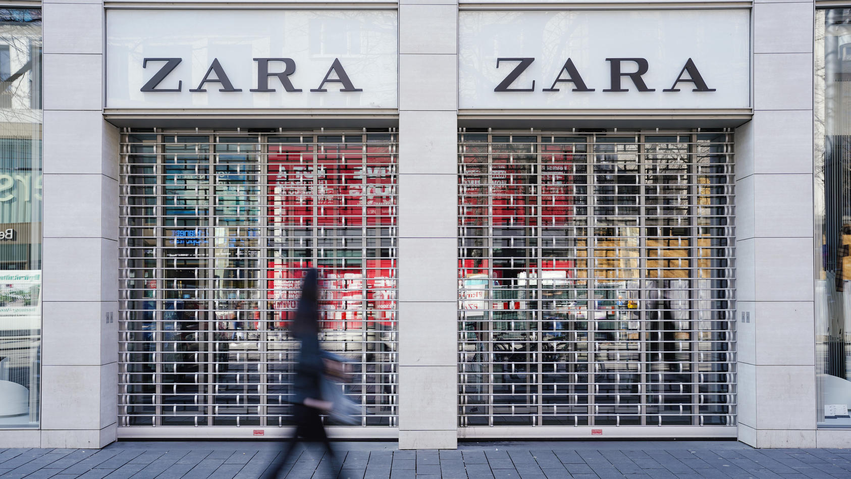 Eine Fußgängerin geht vormittags in der Einkaufsstraße Planken an einem mit Gitter verschlossenen Eingang eines Zara-Bekleidungsgeschäfts vorbei. Der spanische Textilhändler Inditex ist wegen der Coro