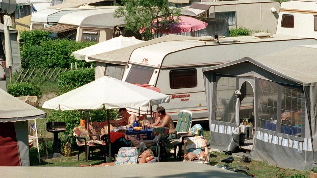 ARCHIV - 08.05.2000, Berlin, Eichhorst: Dicht gedrängt genießen Camper an einem See die Sommersonne. Die Welt entdecken ohne auf Fahrpläne oder Hotels angewiesen zu sein, das fasziniert viele Menschen. Ein Zuhause auf Rädern bietet Mobilität und Bequ