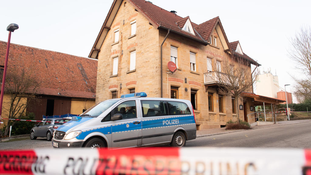 ARCHIV - 24.01.2020, Baden-Württemberg, Rot am See: Nach Schüssen in Rot am See im Nordosten Baden-Württembergs steht ein Polizeiauto hinter einer Absperrung an einem Haus. Hier sind mehrere Menschen getötet worden. (zu dpa: «Prozess um Bluttat in Ro