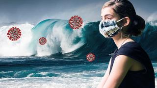 Frau mit Maske blick auf große Welle.