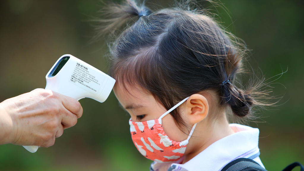 22.06.2020, Südkorea, Daegu: Einem Mädchen wird am ersten Tag der Wiedereröffnung einer Kindertagesstätte die Temperatur gemessen, nachdem die Kindertagesstätten der Region aufgrund der Corona-Pandemie 122 Tage geschlossen waren. Foto: -/YNA/dpa +++