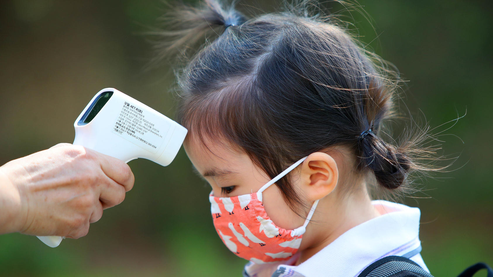 22.06.2020, Südkorea, Daegu: Einem Mädchen wird am ersten Tag der Wiedereröffnung einer Kindertagesstätte die Temperatur gemessen, nachdem die Kindertagesstätten der Region aufgrund der Corona-Pandemie 122 Tage geschlossen waren. Foto: -/YNA/dpa +++ 