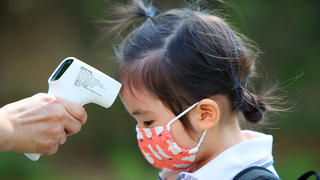 22.06.2020, Südkorea, Daegu: Einem Mädchen wird am ersten Tag der Wiedereröffnung einer Kindertagesstätte die Temperatur gemessen, nachdem die Kindertagesstätten der Region aufgrund der Corona-Pandemie 122 Tage geschlossen waren. Foto: -/YNA/dpa +++ dpa-Bildfunk +++
