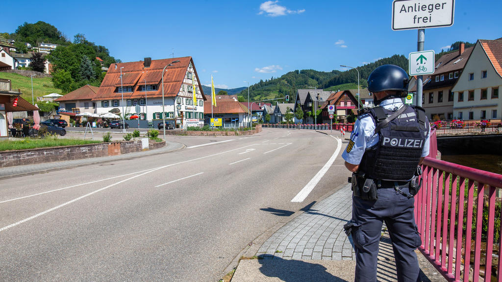 Baden-Württemberg, Oppenau: Ein Polizist sichert eine Straße im Ortskern. Ein Großaufgebot der Polizei sucht seit dem Vormittag einen bewaffneten Mann. 