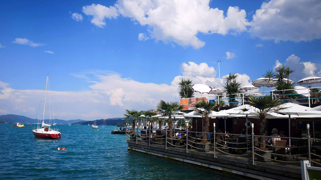 08.07.2020, Österreich, Velden: Menschen sitzen in einem Lokal in der Veldener Bucht am Wörthersee. In dem Touristenort gilt künftig von 21.00 bis 2.00 Uhr im öffentlichen Raum eine Maskenpflicht. Foto: Barbara Gindl/APA/dpa +++ dpa-Bildfunk +++